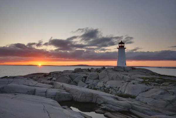 Peggy's Cove lighthouse on granite rocks at sunset